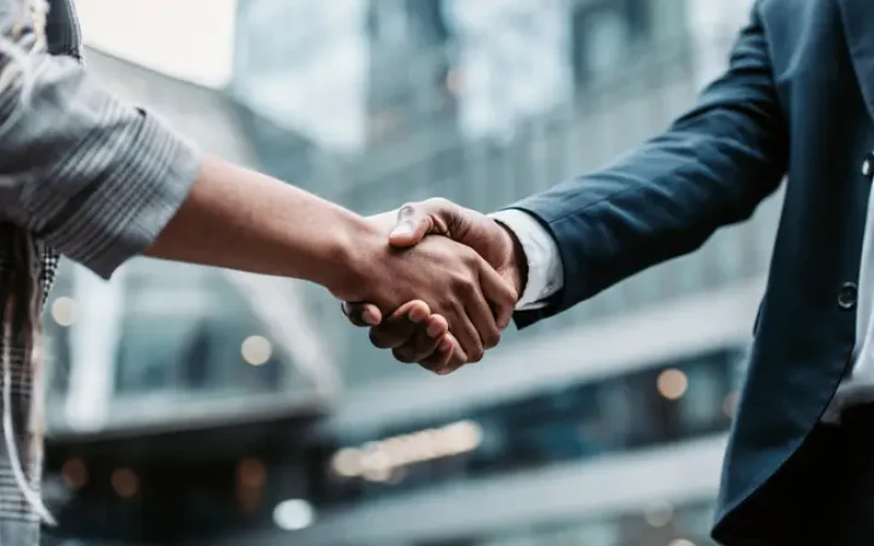Meeting success. Two business persons shaking hands standing outside Meeting success. Two business persons shaking hands standing outside