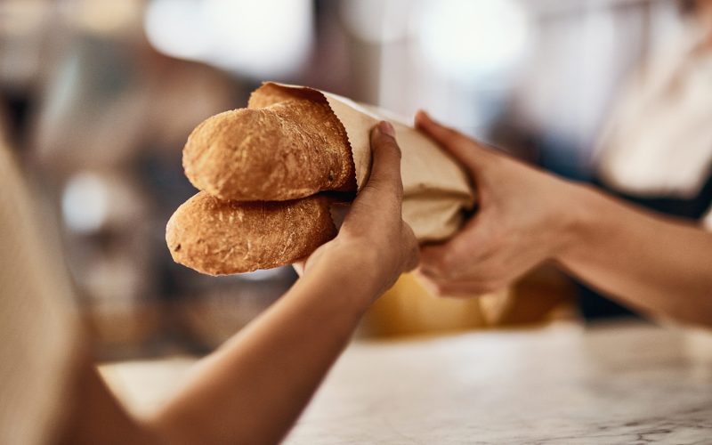 Cropped shot of a woman buying freshly made baguettes at a bakery